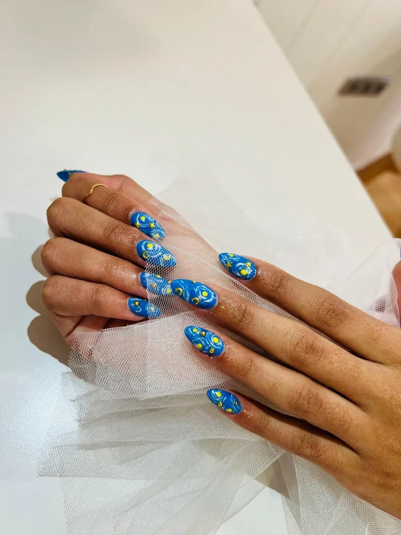Nail art azul noche estrellada con lunas y puntos dorados